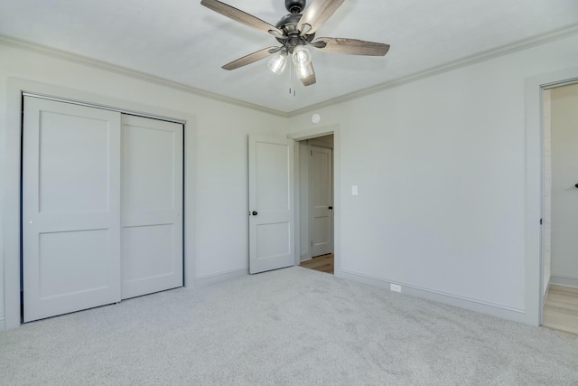 unfurnished bedroom featuring crown molding, light carpet, ceiling fan, and a closet