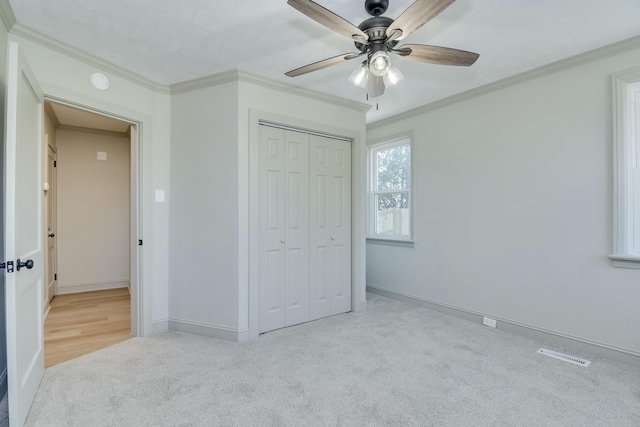 unfurnished bedroom with ornamental molding, light carpet, ceiling fan, and a closet