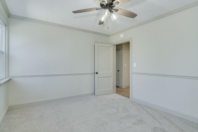 carpeted empty room with ceiling fan and ornamental molding