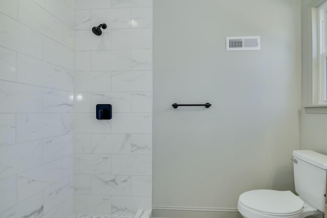 bathroom featuring a tile shower and toilet