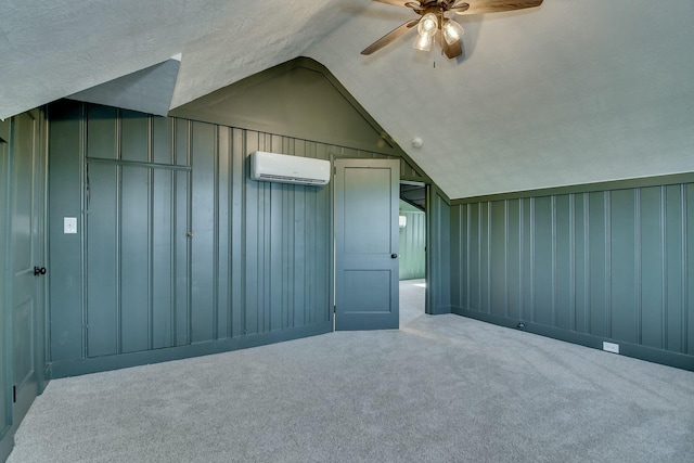 bonus room featuring lofted ceiling, a wall mounted AC, a textured ceiling, carpet floors, and ceiling fan