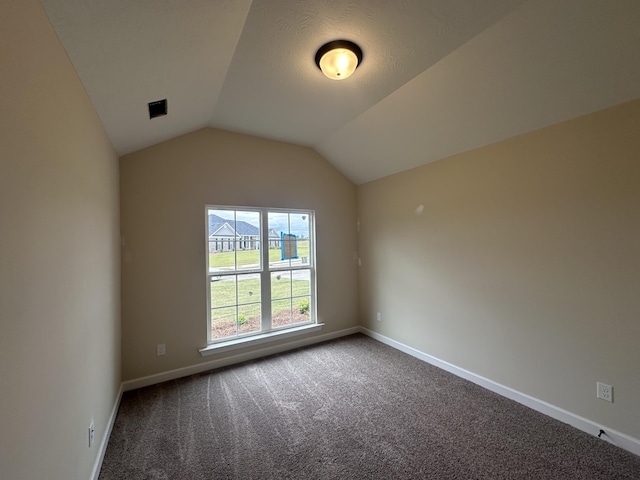 carpeted spare room with vaulted ceiling