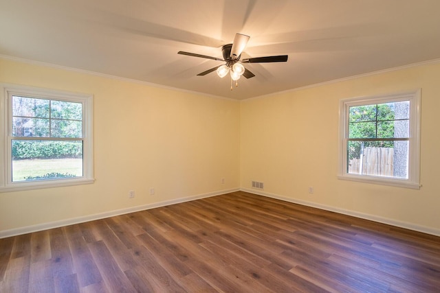 empty room with ornamental molding, visible vents, dark wood finished floors, and baseboards