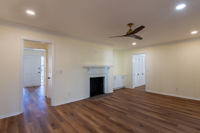 unfurnished living room featuring dark wood-type flooring, a fireplace, baseboards, and ornamental molding