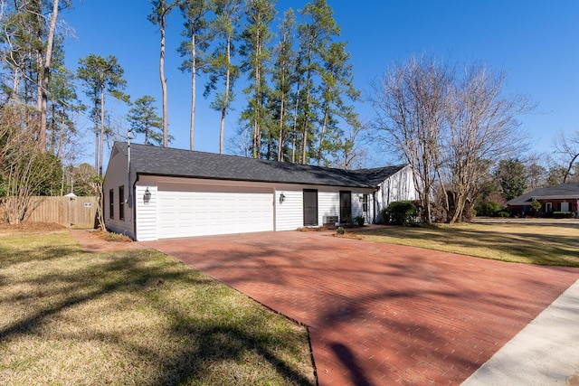 view of front of home with an attached garage, fence, decorative driveway, and a front yard