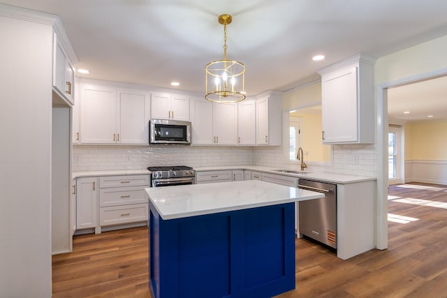 kitchen featuring stainless steel appliances, white cabinetry, a sink, and wood finished floors