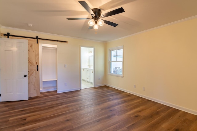 unfurnished bedroom with a barn door, dark wood-type flooring, and crown molding