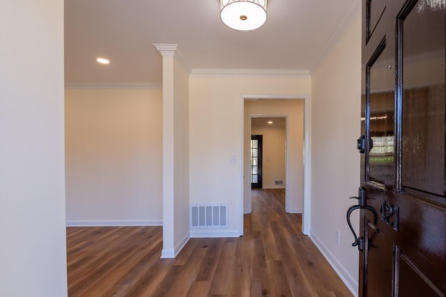 hallway with dark wood-style floors, baseboards, visible vents, and crown molding