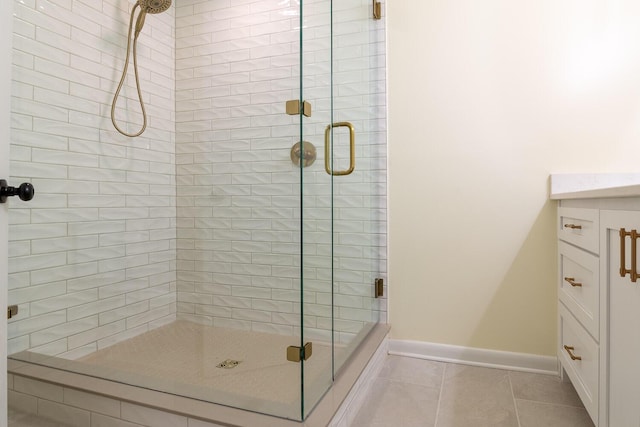 full bath with a stall shower, tile patterned flooring, vanity, and baseboards