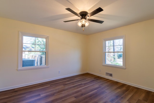 spare room featuring a ceiling fan, baseboards, visible vents, and dark wood-style flooring