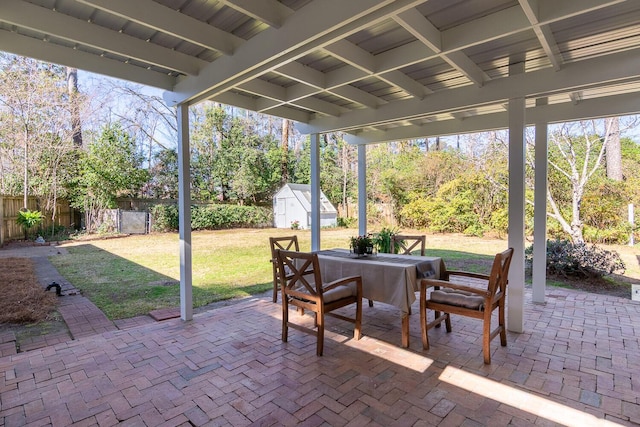 view of patio / terrace with an outbuilding, a shed, outdoor dining space, and a fenced backyard