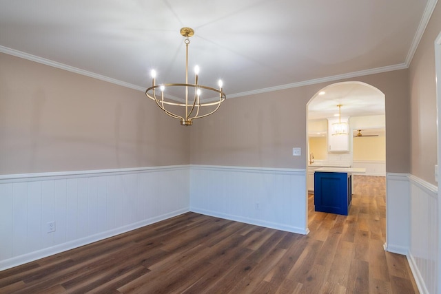 spare room featuring arched walkways, wainscoting, dark wood finished floors, and a notable chandelier