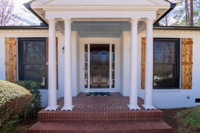 property entrance featuring a porch and brick siding