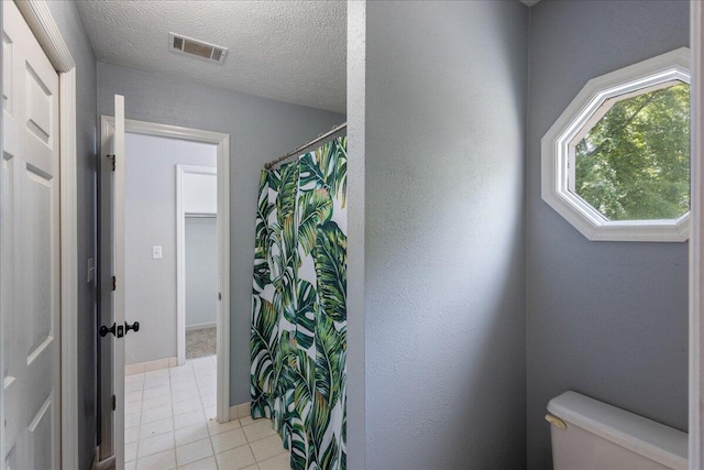 bathroom featuring tile patterned floors, a textured ceiling, and toilet