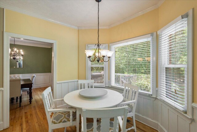 dining space with crown molding, plenty of natural light, light wood-type flooring, and an inviting chandelier