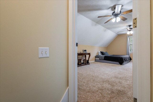 bedroom with a textured ceiling, carpet floors, vaulted ceiling, and ceiling fan