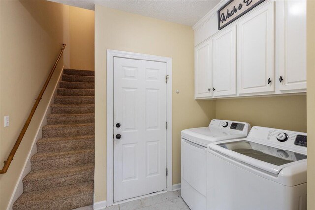 washroom with cabinets, independent washer and dryer, and a textured ceiling