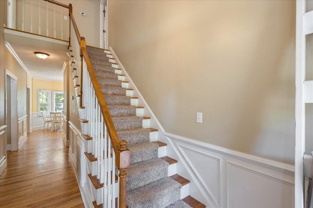 stairs with crown molding and wood-type flooring