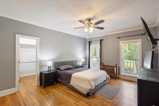 bedroom with ceiling fan, ornamental molding, a textured ceiling, and light hardwood / wood-style flooring