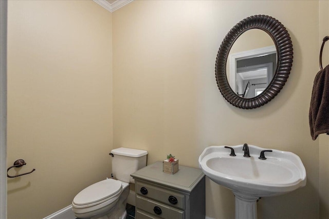 bathroom featuring toilet, ornamental molding, and sink