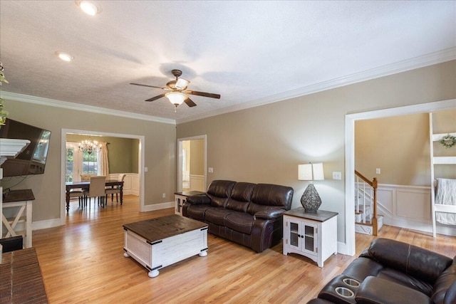 living room featuring a textured ceiling, ceiling fan with notable chandelier, light hardwood / wood-style floors, and ornamental molding