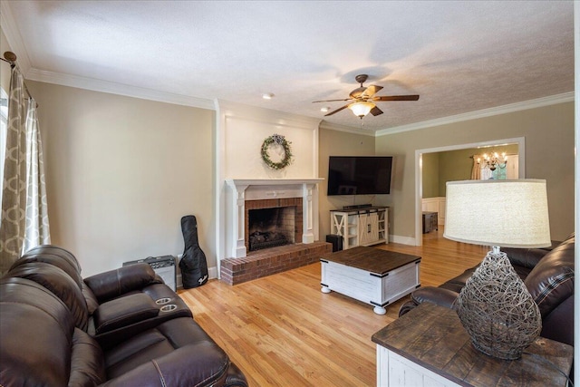 living room with a brick fireplace, ceiling fan, ornamental molding, a textured ceiling, and wood-type flooring