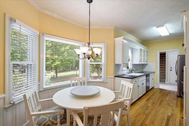 dining space featuring plenty of natural light, crown molding, a textured ceiling, a notable chandelier, and light hardwood / wood-style floors