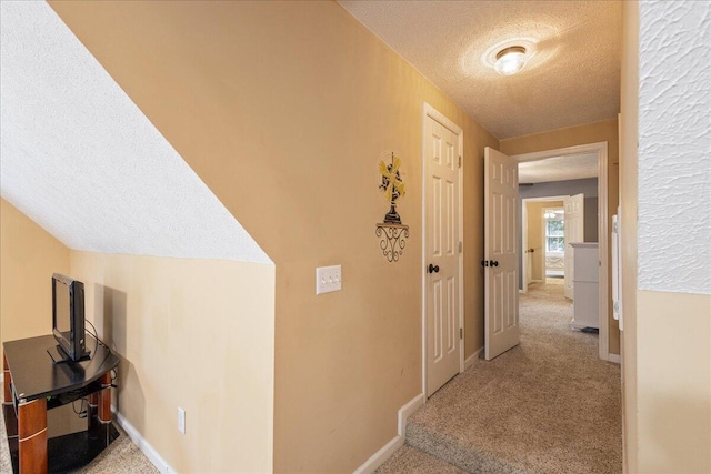 corridor featuring light colored carpet and a textured ceiling