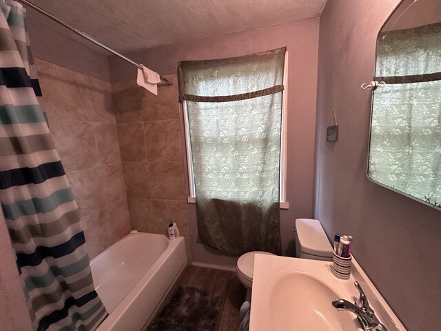 full bathroom featuring hardwood / wood-style floors, toilet, a textured ceiling, and shower / tub combo