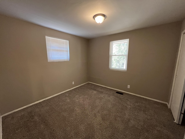 spare room with dark carpet