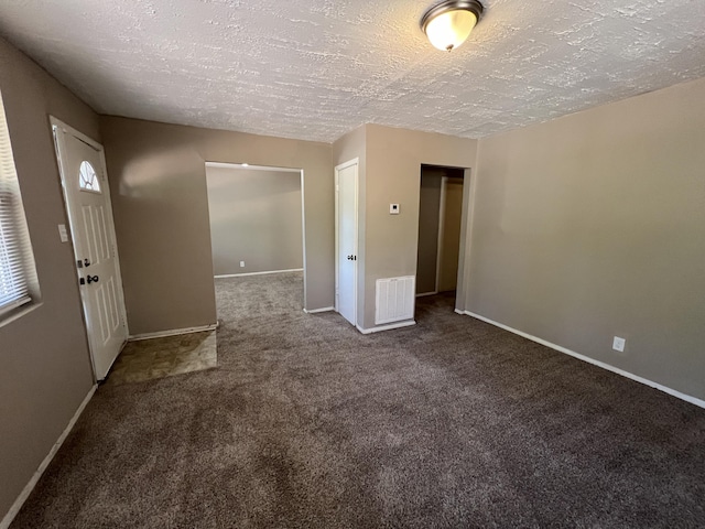 carpeted empty room featuring a textured ceiling