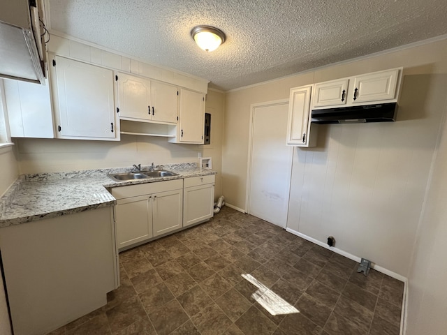 kitchen with a textured ceiling, white cabinetry, and sink