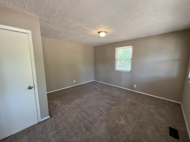 empty room featuring dark colored carpet and a textured ceiling