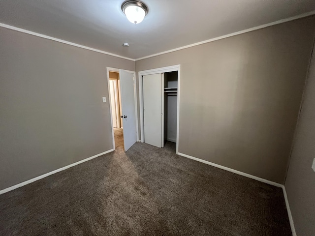 unfurnished bedroom featuring dark carpet, crown molding, and a closet