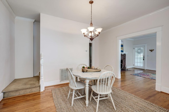 1534 Whitney St, Augusta, GA 30904 - dining room featuring light wood finished floors, a chandelier, ornamental molding, baseboards, and a fireplace