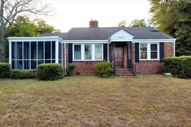 view of front of home with a front yard and a sunroom