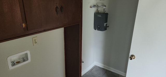 clothes washing area featuring cabinets, tile patterned flooring, and water heater