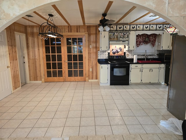 kitchen with stainless steel appliances, arched walkways, wood walls, and a sink