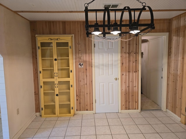 unfurnished dining area with wood walls, visible vents, and light tile patterned flooring