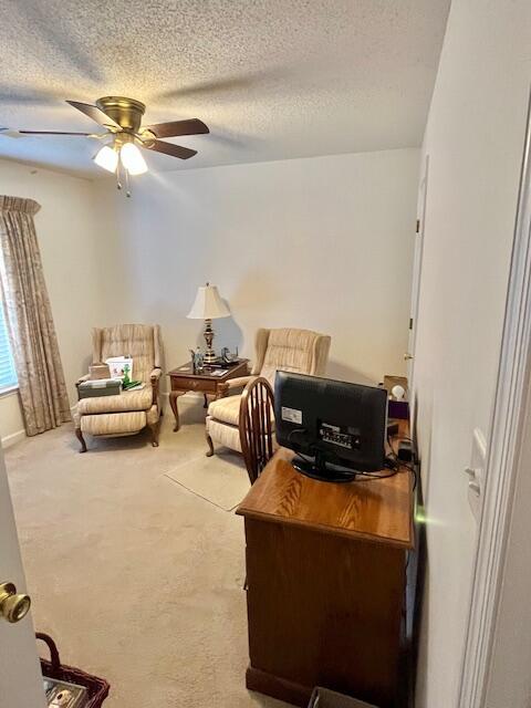 carpeted home office with a ceiling fan and a textured ceiling