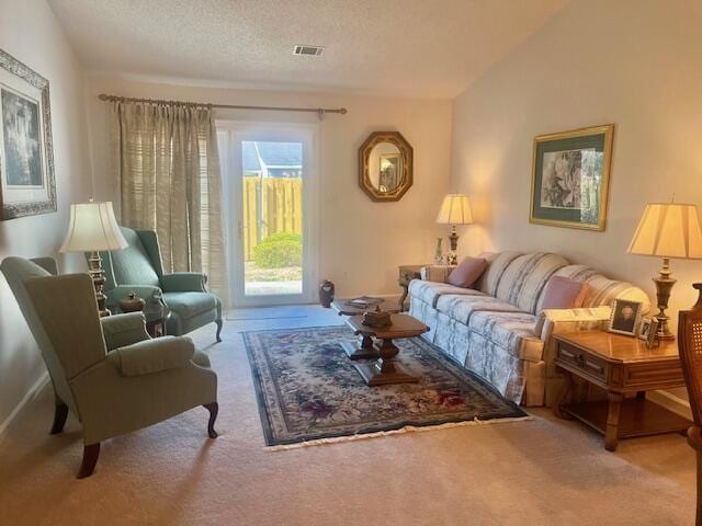 living area with carpet, visible vents, vaulted ceiling, and a textured ceiling