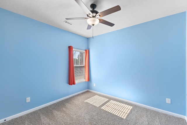 carpeted spare room featuring ceiling fan, visible vents, and baseboards