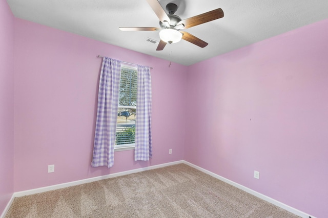 spare room with light carpet, ceiling fan, visible vents, and baseboards