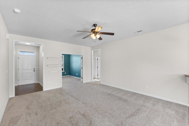 unfurnished room with carpet, visible vents, a textured ceiling, and baseboards