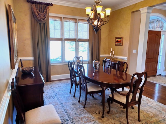 dining space featuring a chandelier, wood finished floors, baseboards, and ornamental molding