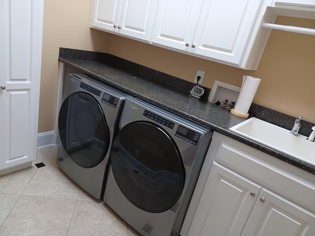 washroom with light tile patterned floors, a sink, cabinet space, and separate washer and dryer