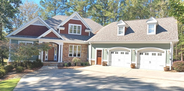 craftsman house with concrete driveway, stone siding, a garage, and roof with shingles