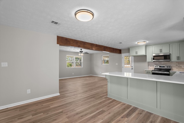 kitchen featuring kitchen peninsula, appliances with stainless steel finishes, decorative backsplash, and ceiling fan