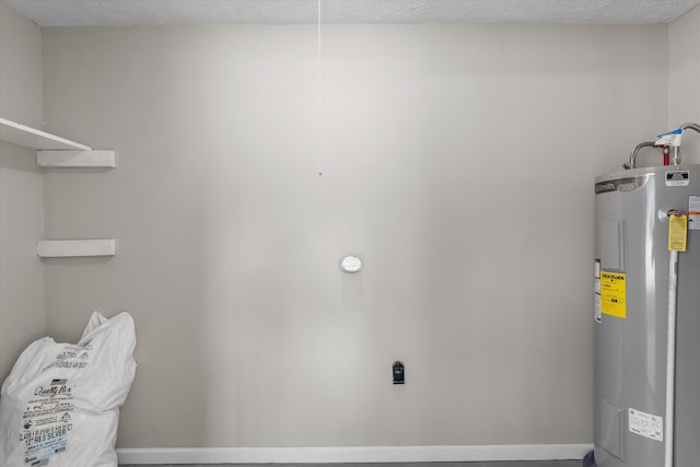 clothes washing area featuring electric water heater and a textured ceiling