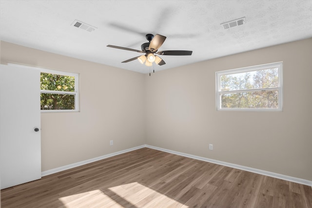 unfurnished room featuring hardwood / wood-style flooring, ceiling fan, and a healthy amount of sunlight